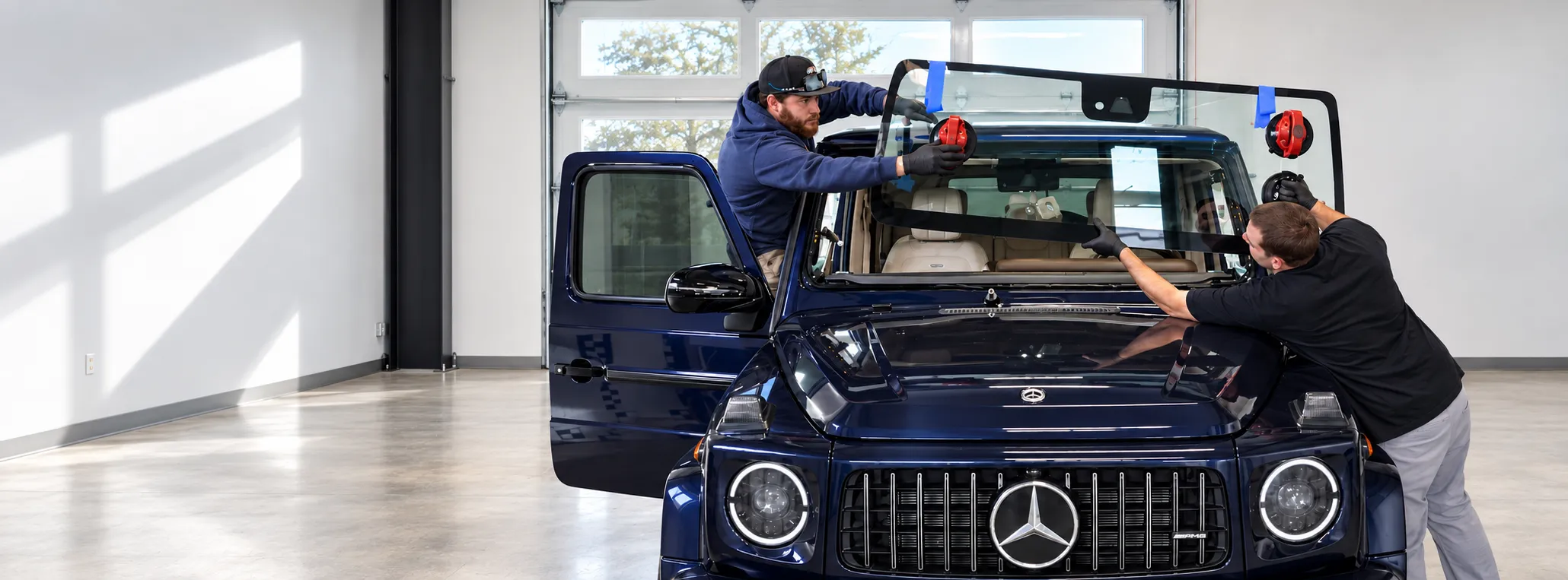 Technicians installing a windshield on a Mercedes-Benz G-Class in our Truckee shop.