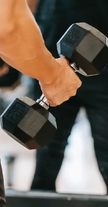Close-up of a person holding a black hex dumbbell during a strength-training workout.
