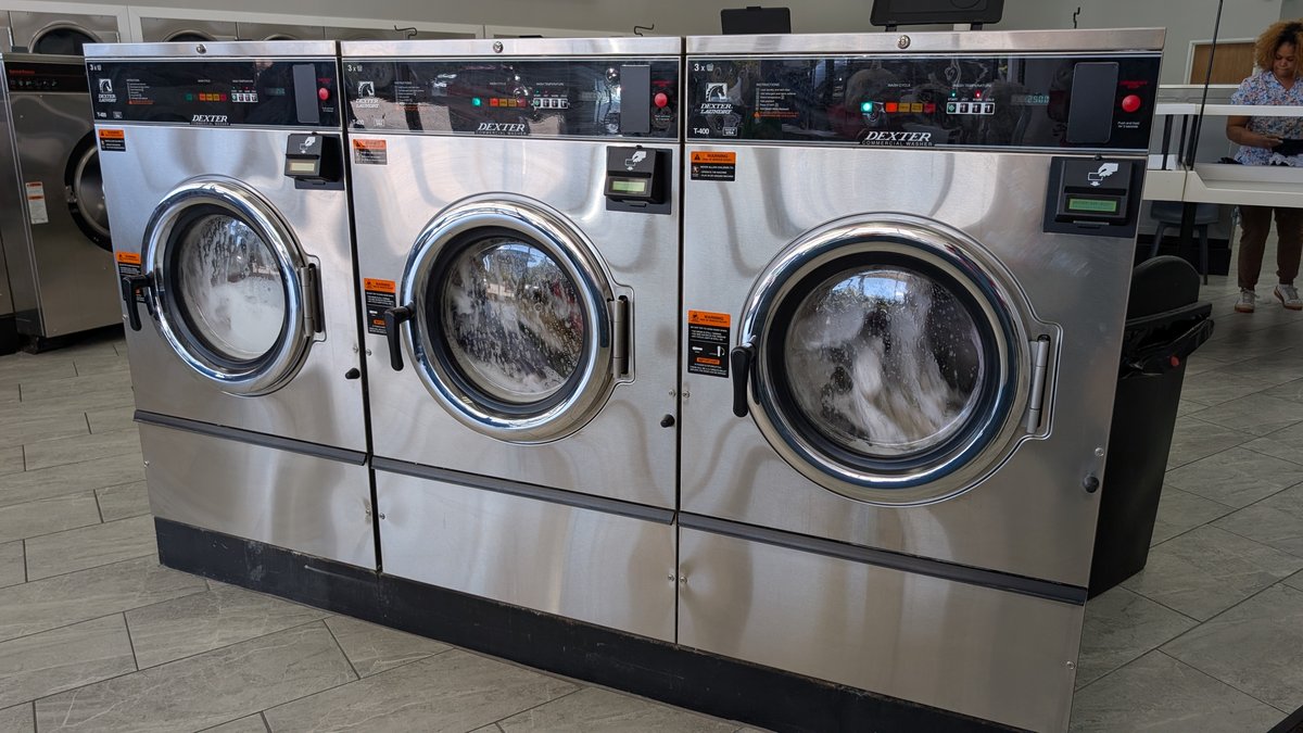 Dexter commercial washers mid-cycle with suds visible through the doors