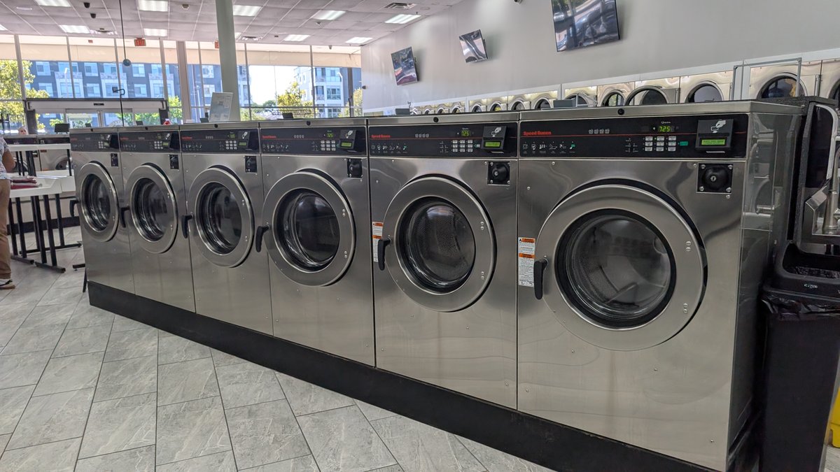 Bright row of Speed Queen washers along the windows at Lafayette Laundromat