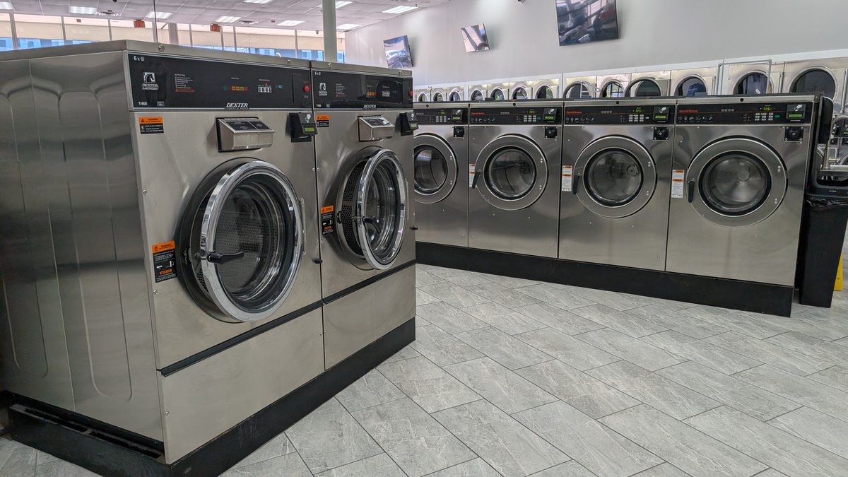 Two large Dexter T-900 washers beside a row of Speed Queen machines
