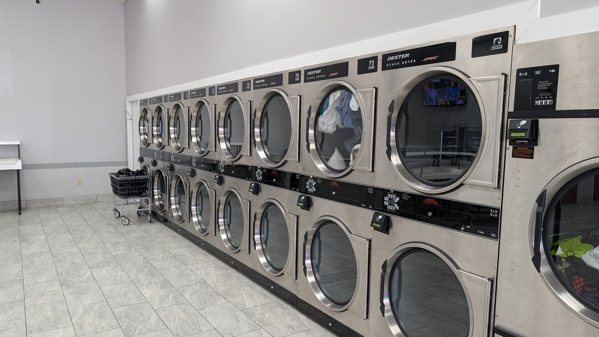 Long row of Dexter stack dryers with a laundry cart
