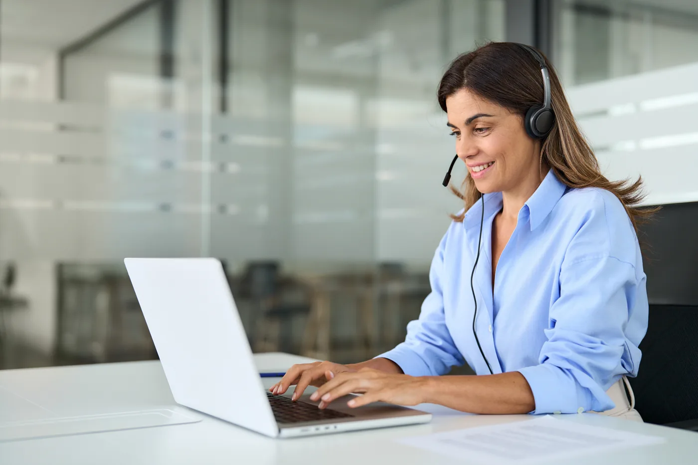 Live chat agent on a headset answering customer chats on a laptop