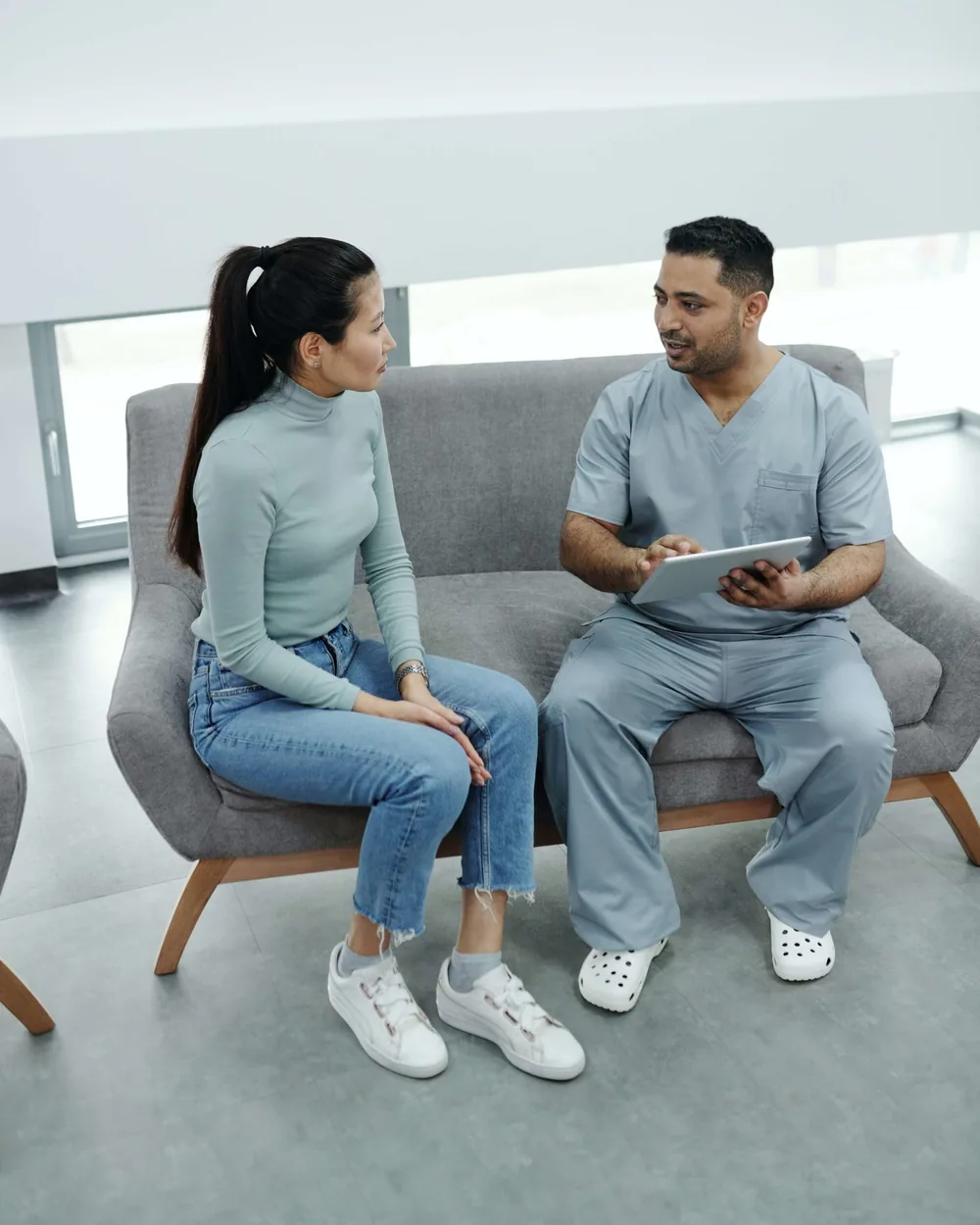Clinician reviewing a tablet with a patient, backed by healthcare IT support