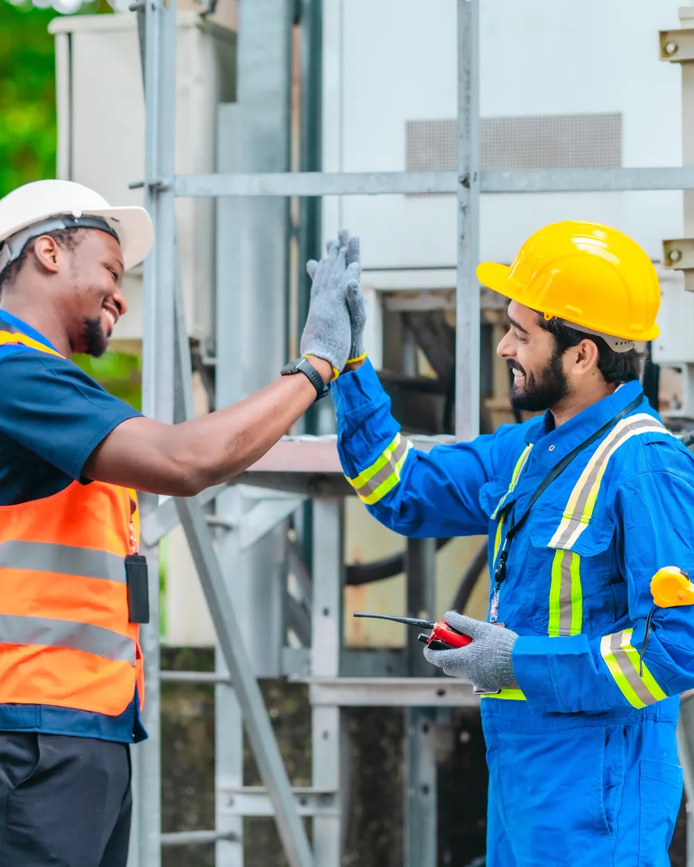 Telecom field technicians in hard hats shaking hands beside network equipment