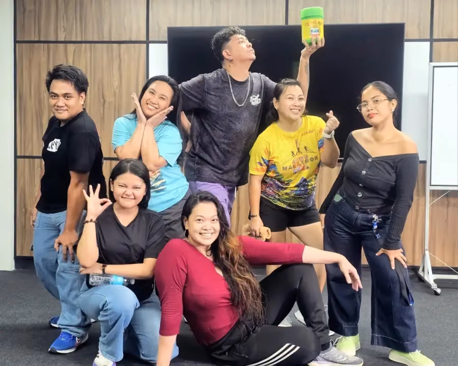 Teammates striking playful poses together in a meeting room