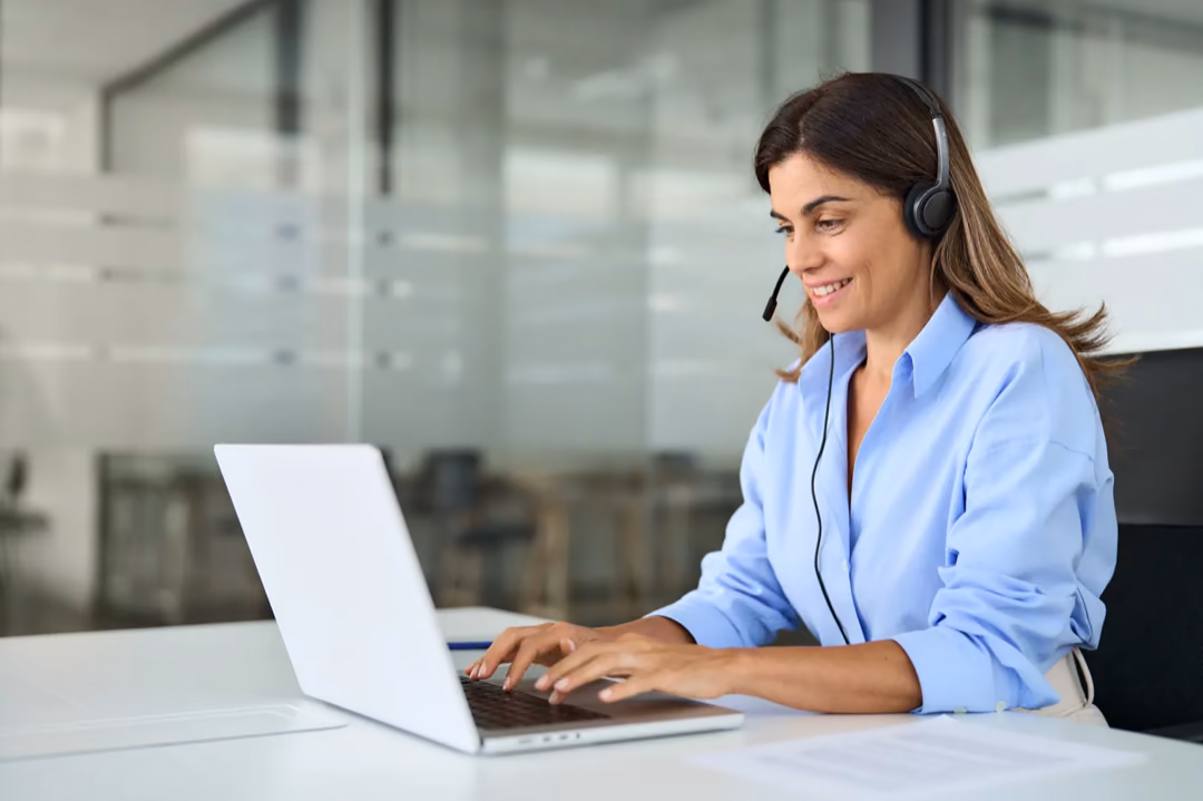 Live chat agent on a headset answering customer chats on a laptop