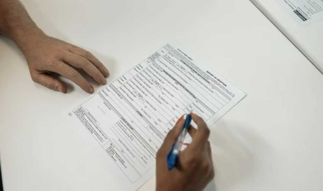 A hand filling out a donation form