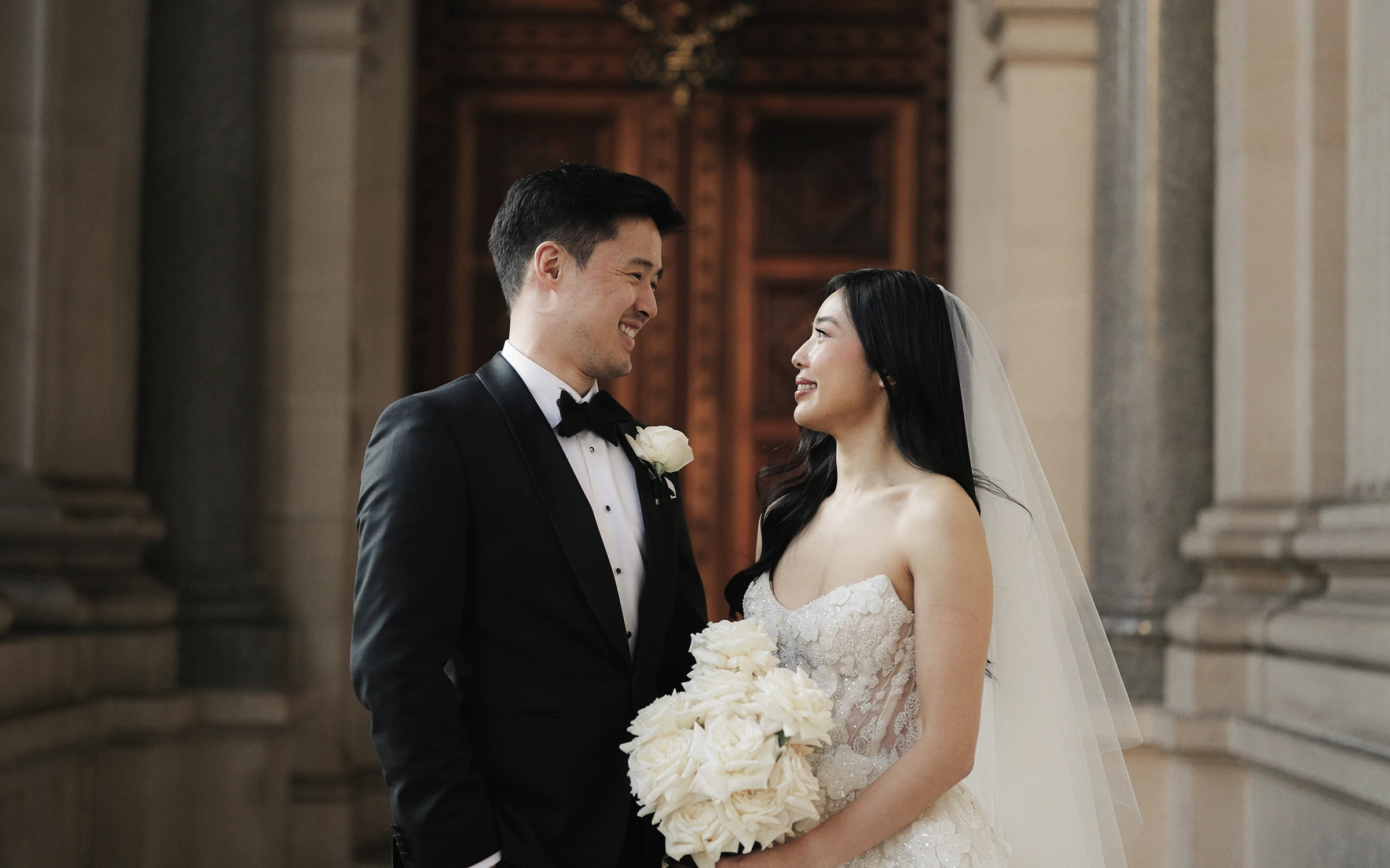 Couple smiling at each other beside stone columns