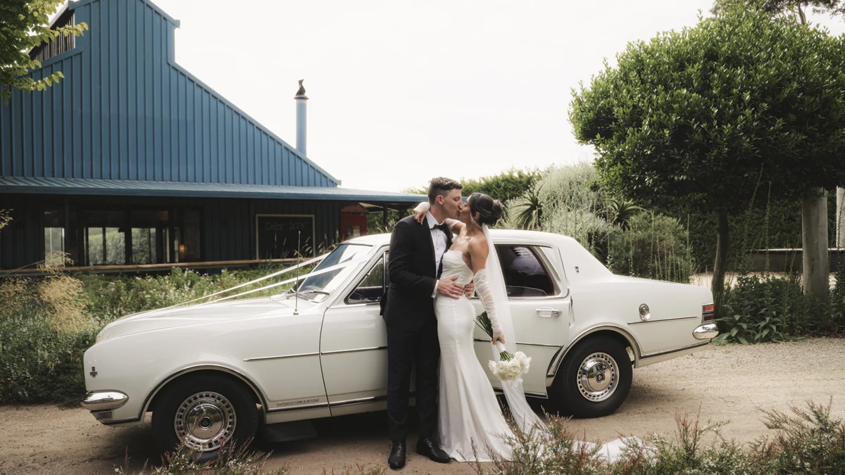 Couple kissing beside a white classic car
