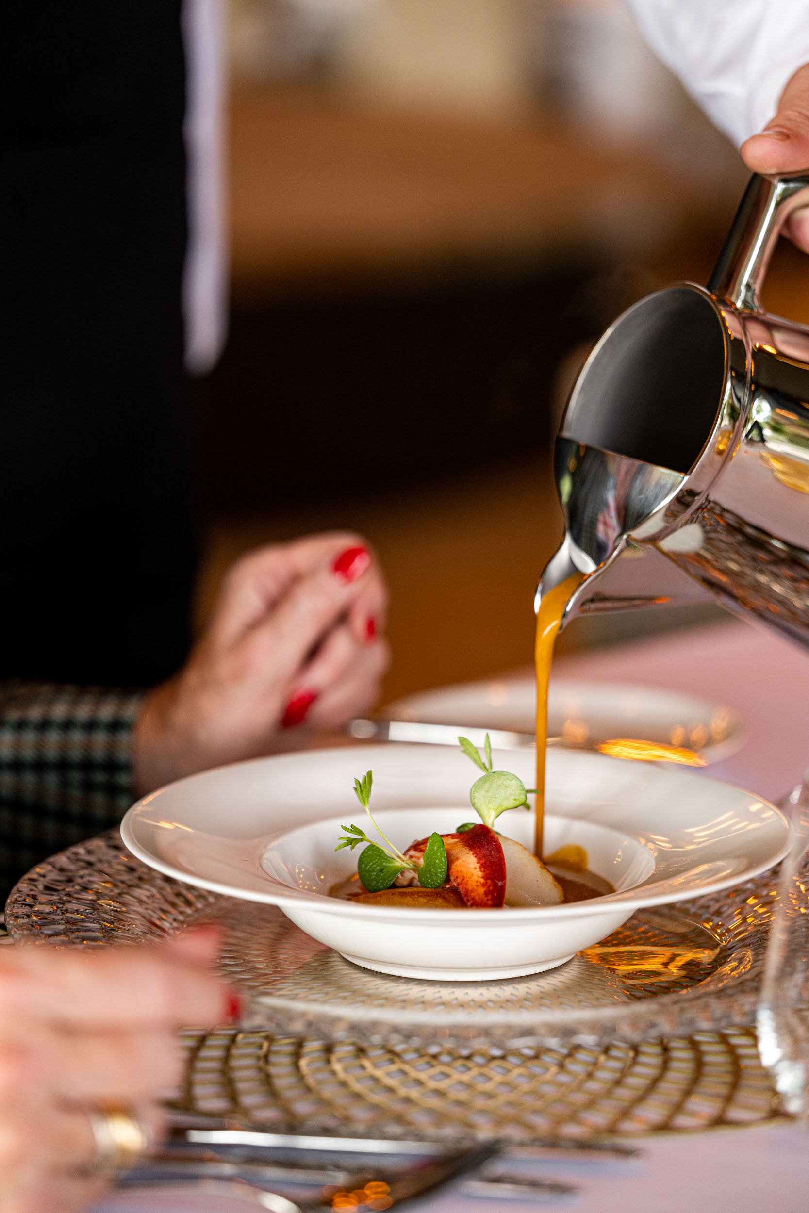 Kreeftenbisque wordt aan tafel over het voorgerecht geschonken