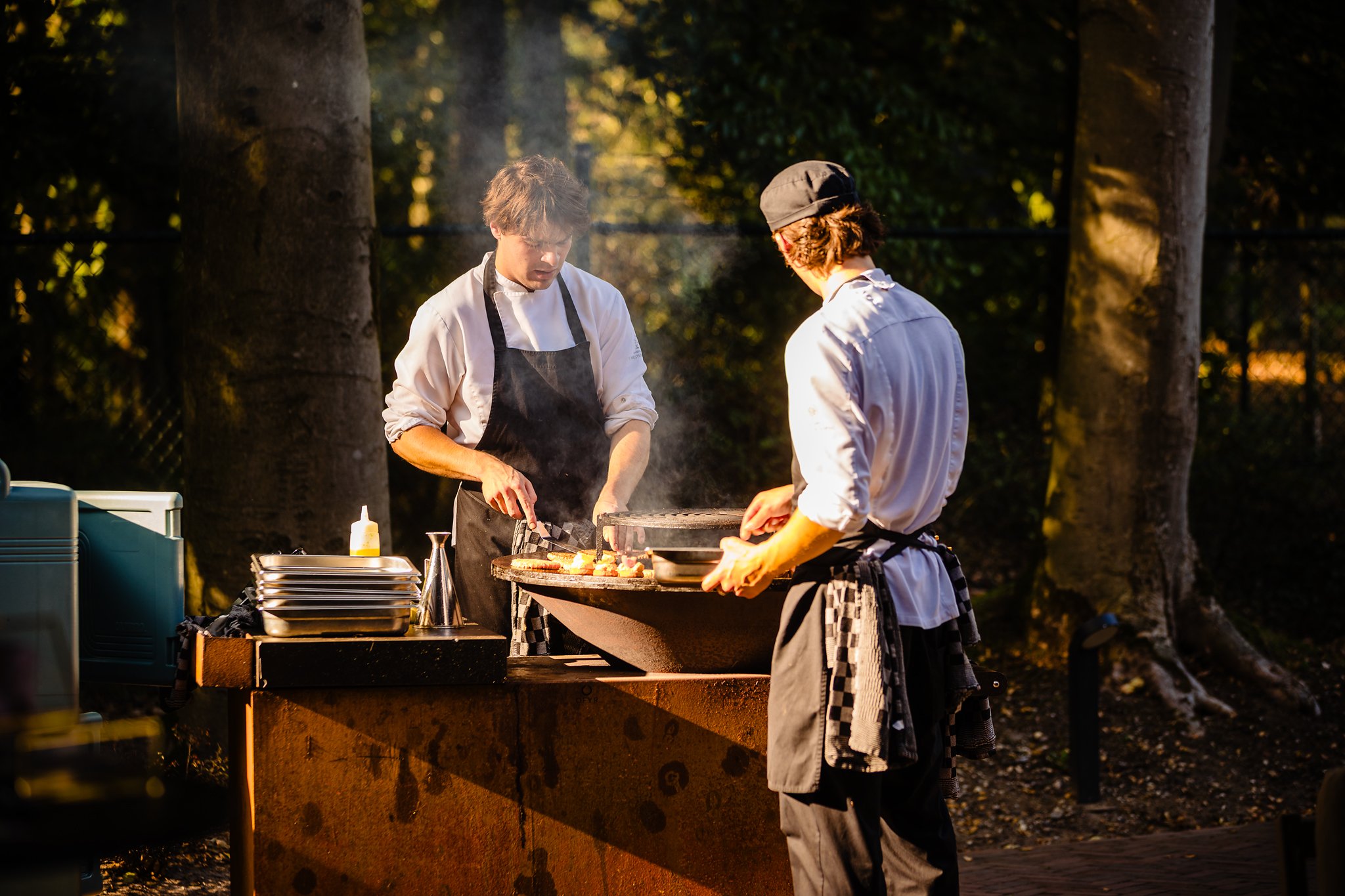 Twee koks bereiden gerechten op de vuurschaal tijdens een barbecue