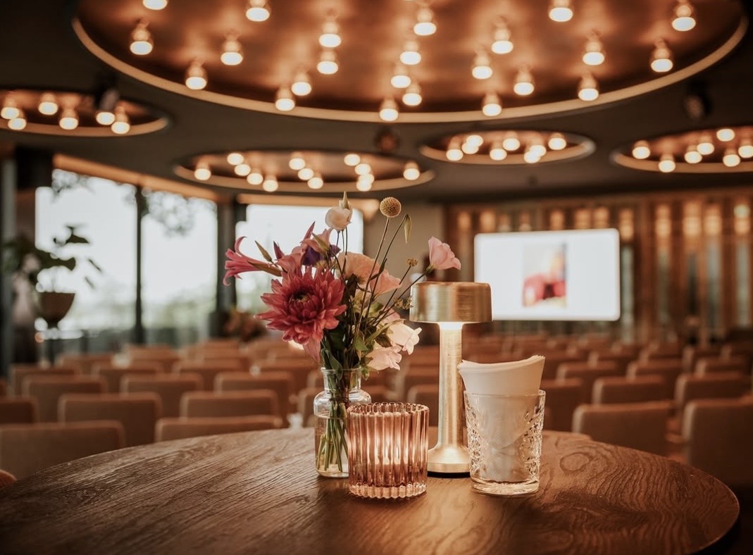 Tafel met bloemen in Zicht, met de zaal in opstelling op de achtergrond