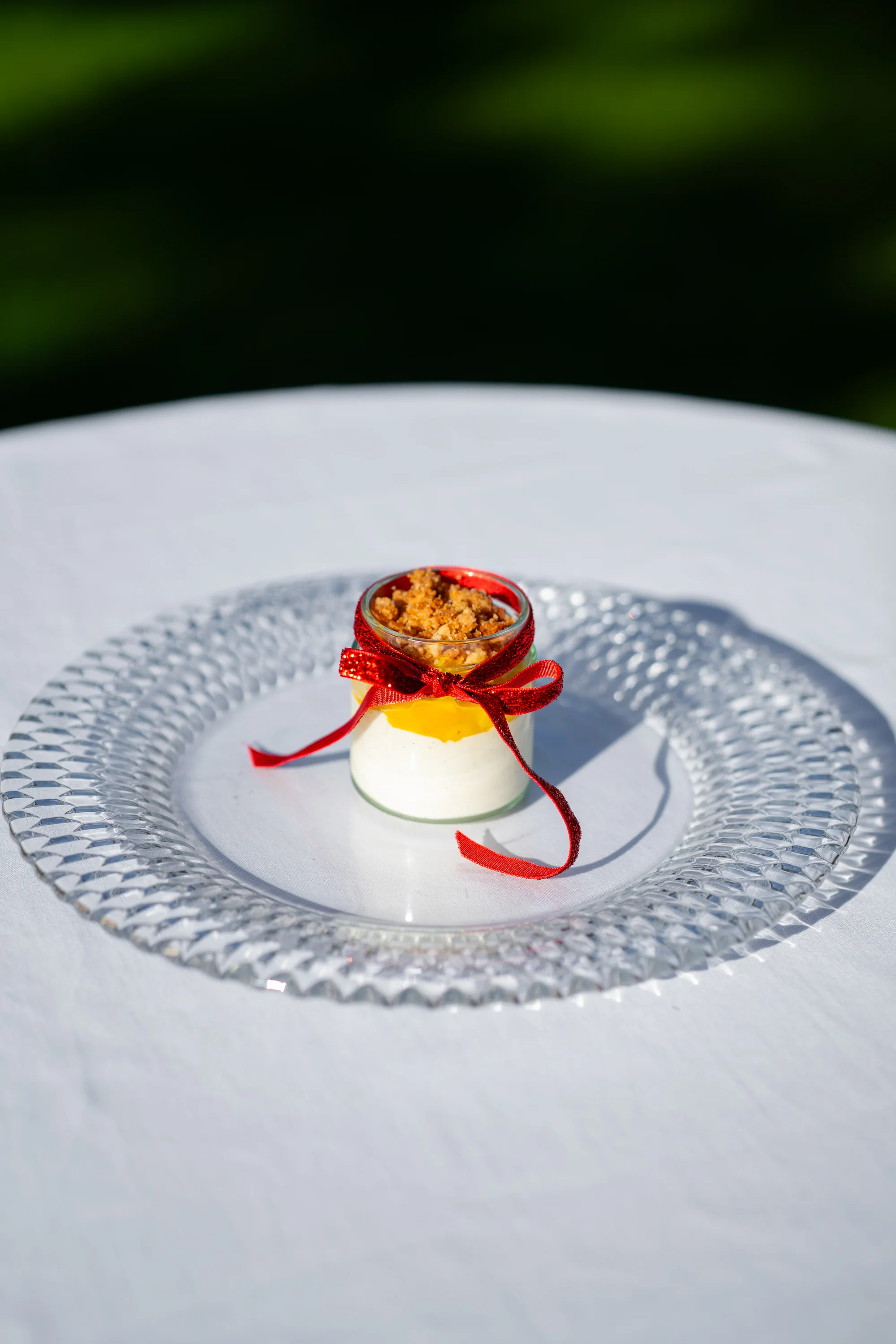 Panna cotta van tonkaboon met mango-passievruchtcompote in een glaasje met rood lint