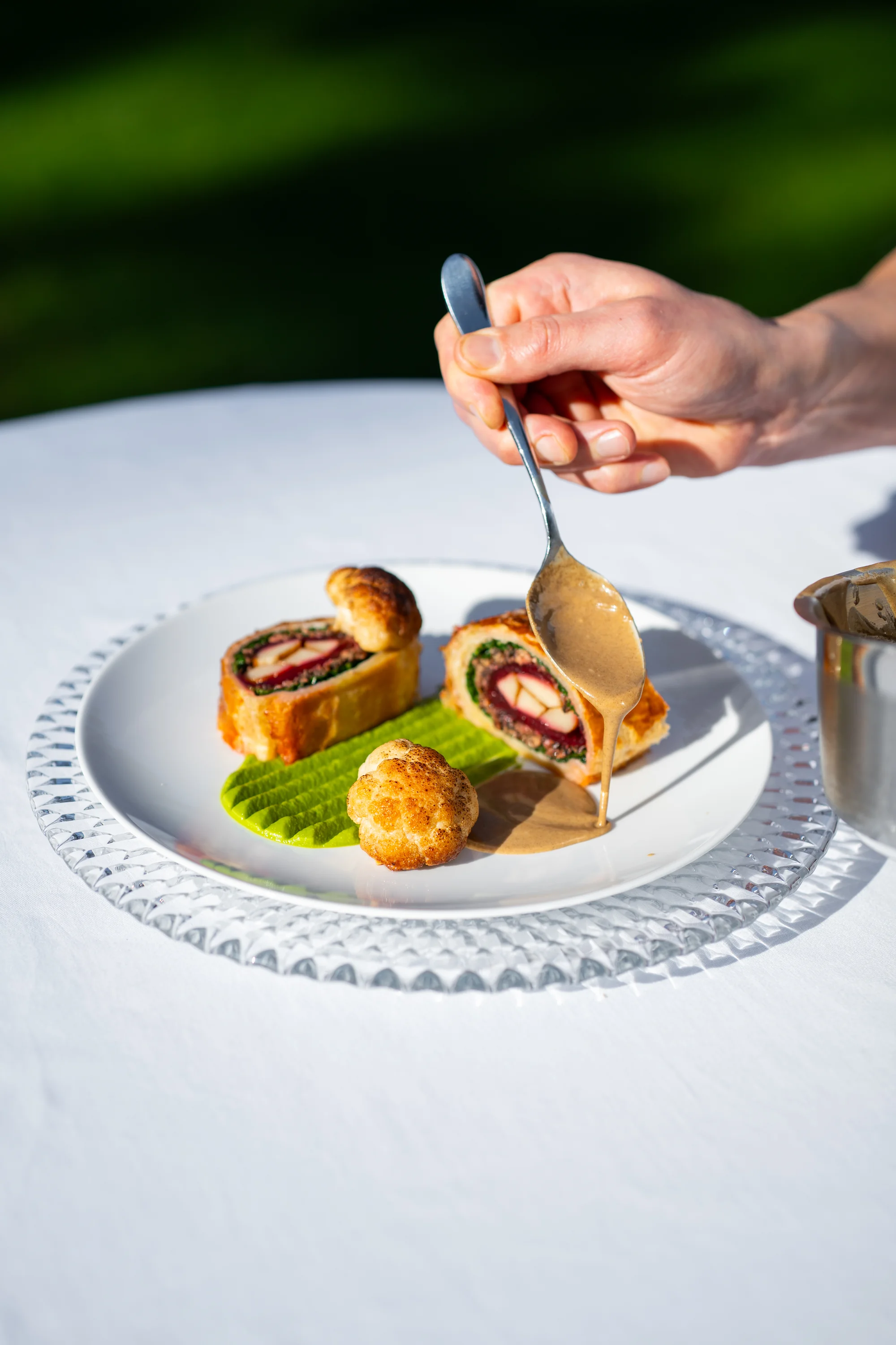 Wellington van boleet en rode biet met doperwtencrème, waarover saus van eekhoorntjesbrood wordt geschept