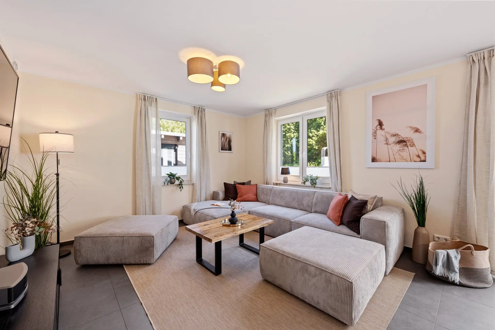 Wohnbereich mit grauem Ecksofa und großen Fenstern
