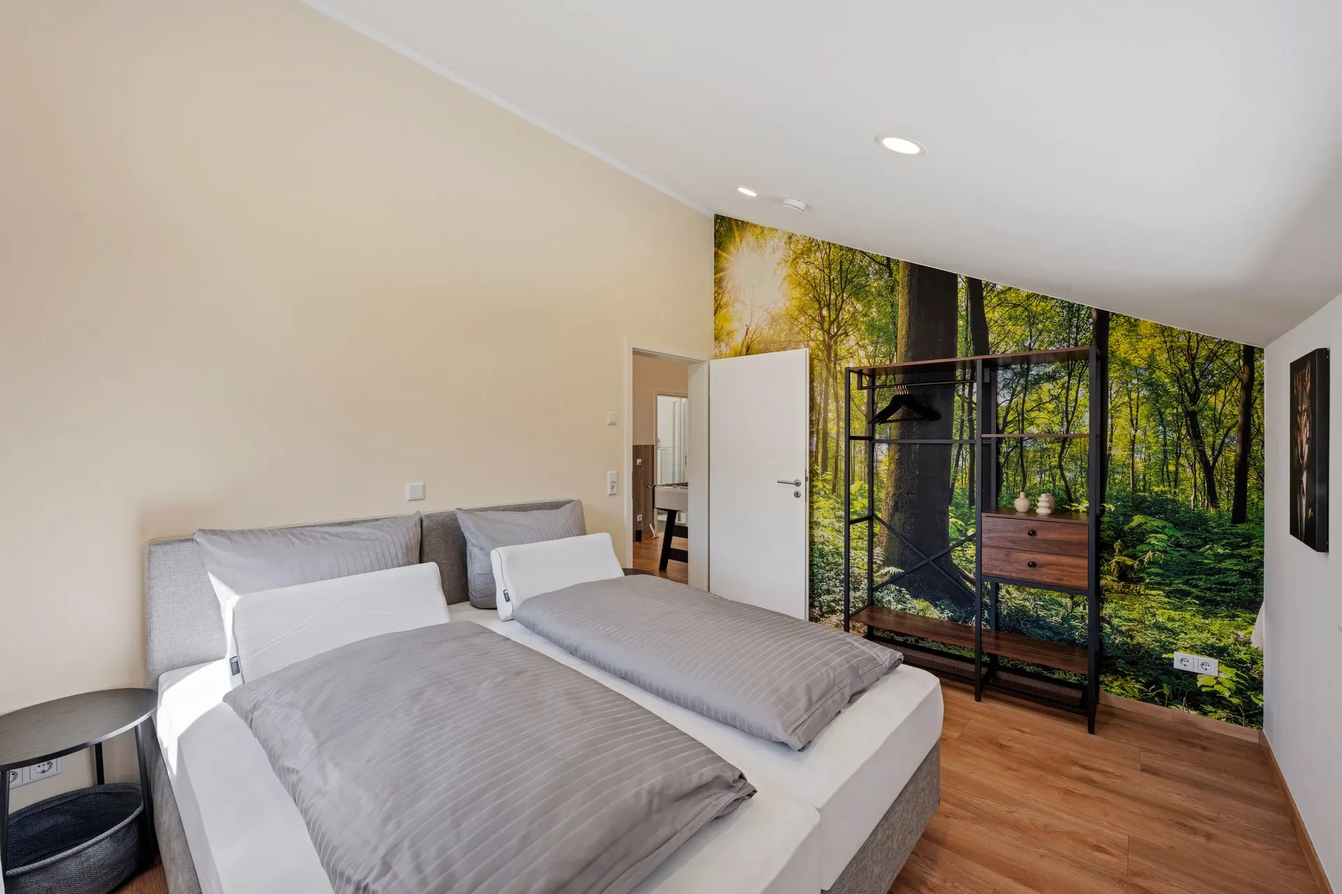 Schlafzimmer mit zwei Betten und Waldmotiv an der Wand
