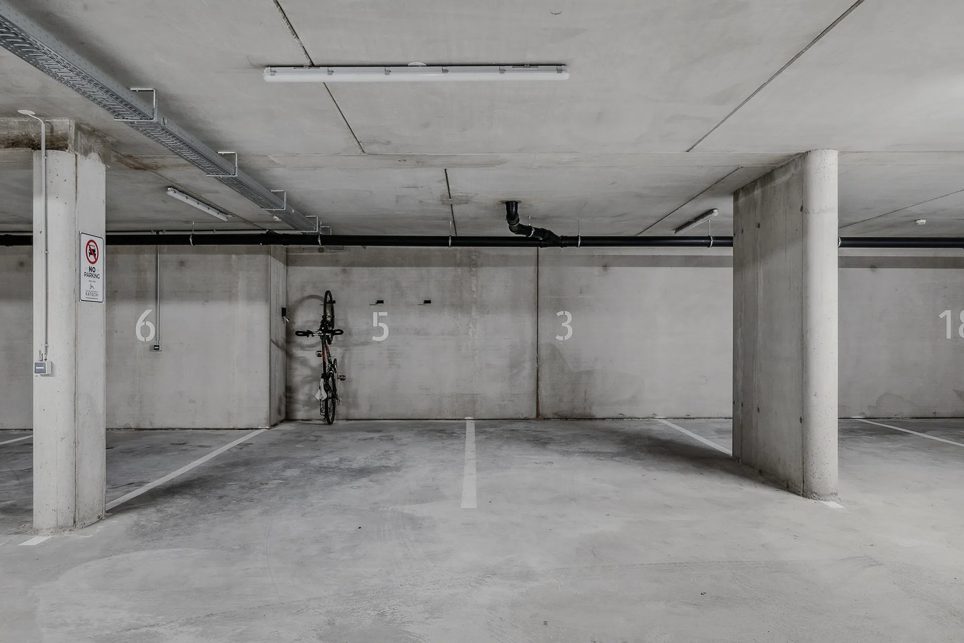 Tiefgarage mit nummerierten Stellplätzen und Fahrradhalterung