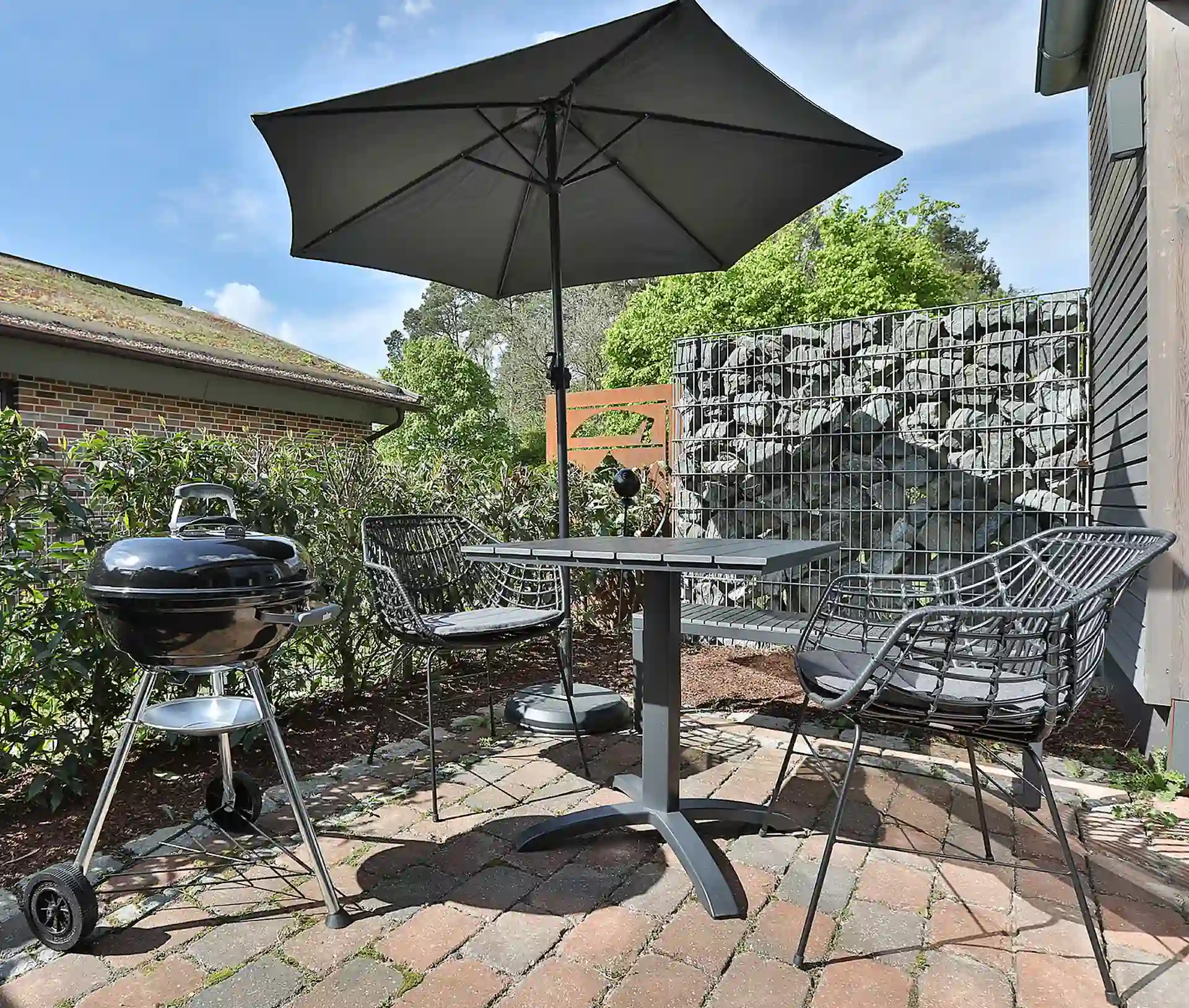 Terrasse mit Sonnenschirm und Blick zum Grill