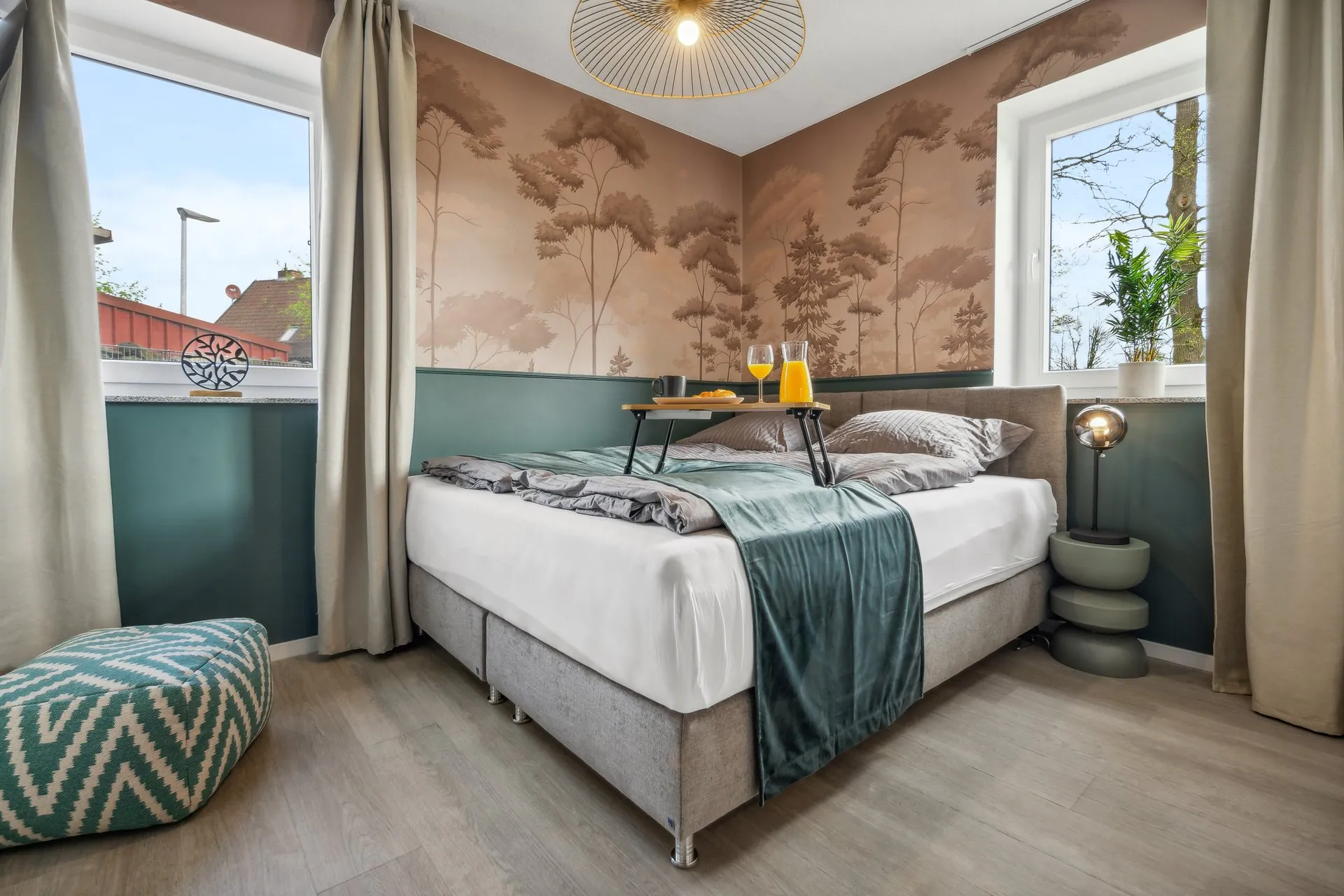 Schlafzimmer mit Waldmotiv-Wandbild und Frühstückstablett