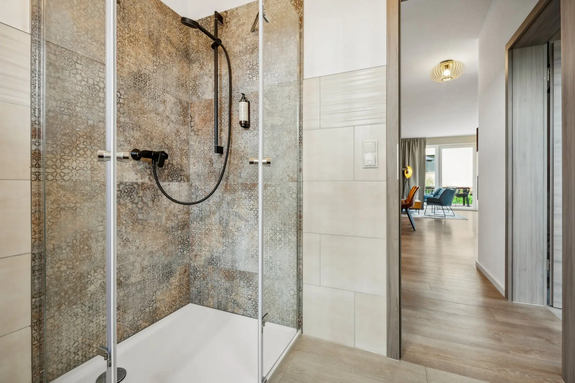 Dusche mit gemustertem Fliesenspiegel hinter Glastür