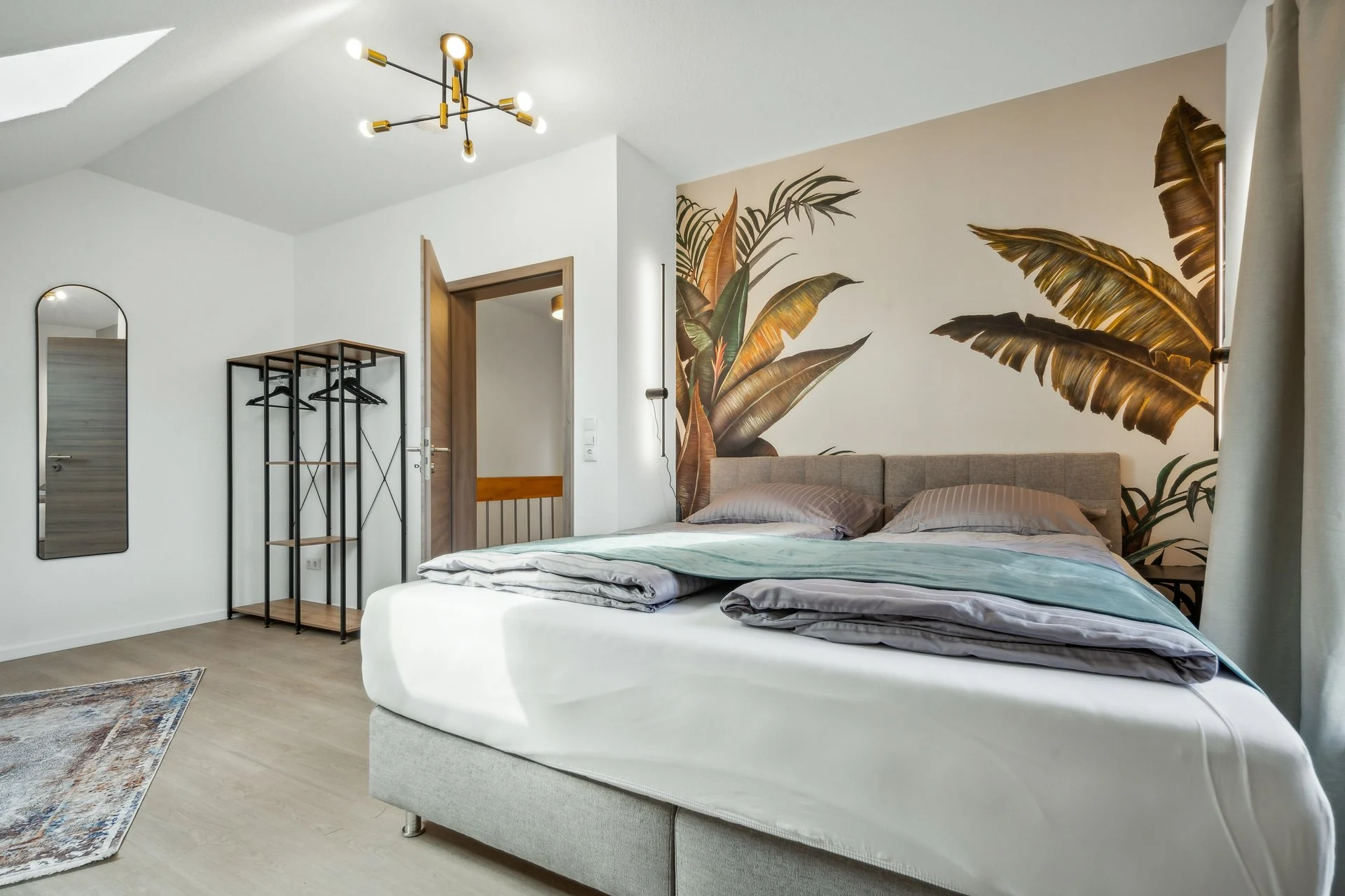 Schlafzimmer mit Bananenblatt-Wandbild und Dachschräge