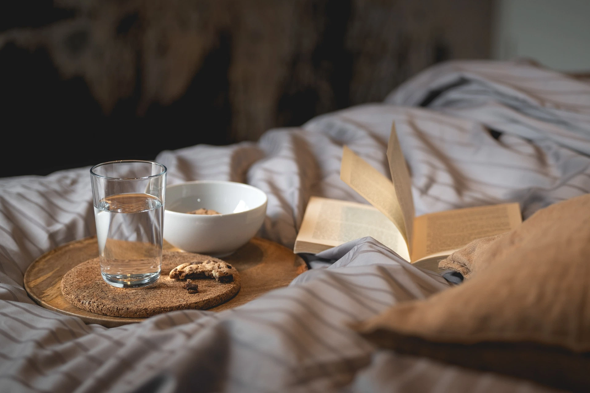 Frühstückstablett mit Wasser und Buch im Bett