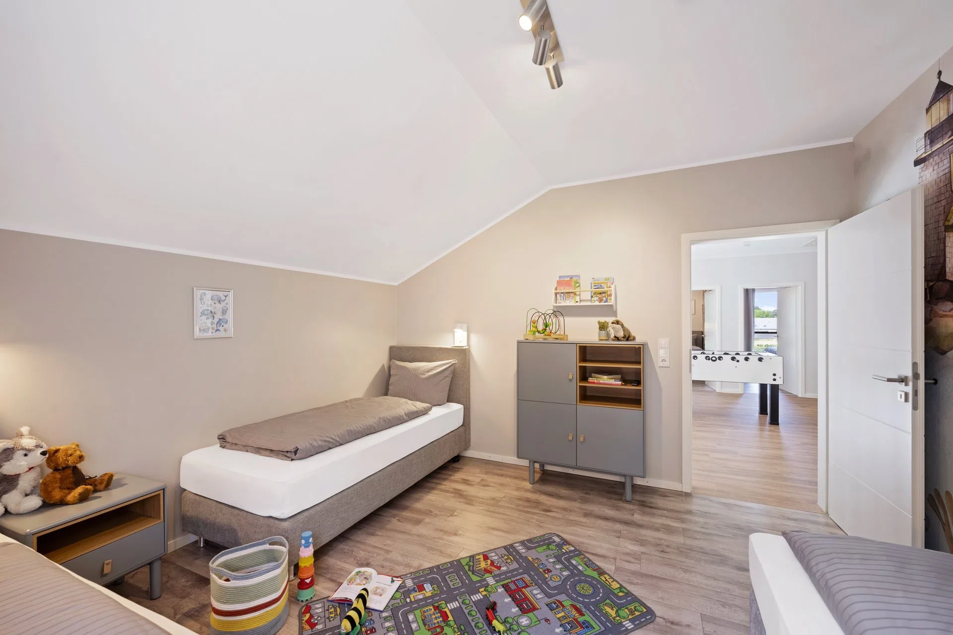Kinderzimmer mit Spielteppich und Blick zum Kickerraum