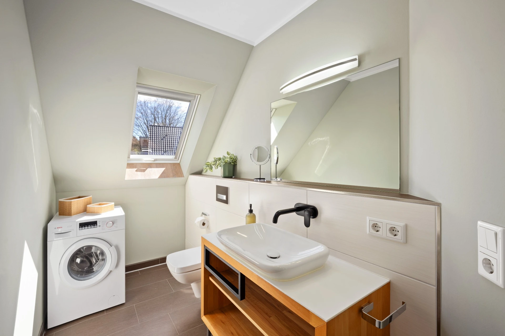 Badezimmer mit Waschmaschine und Holzwaschtisch