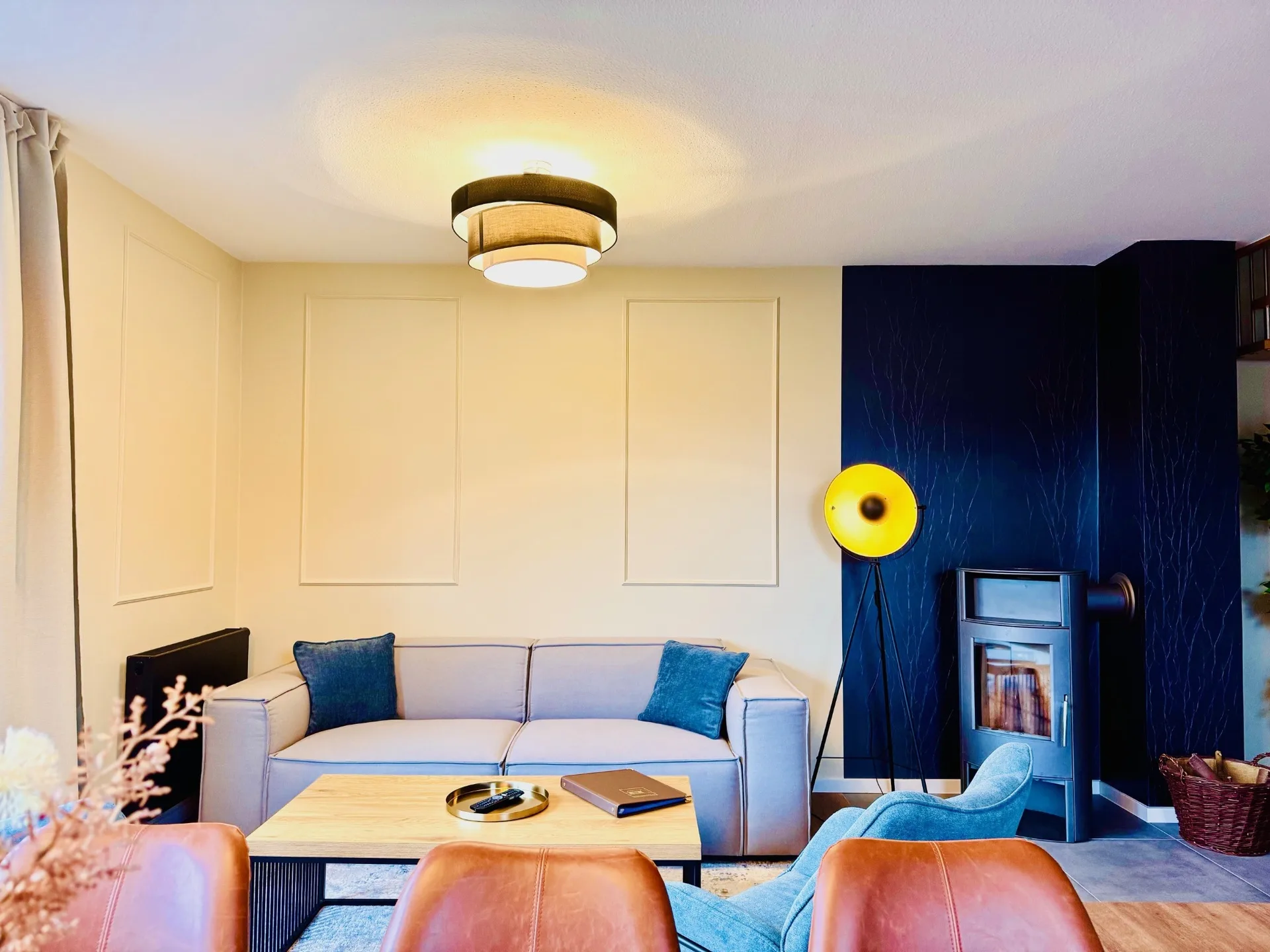 Wohnzimmer mit Sofa und Kaminofen vor blauer Wand