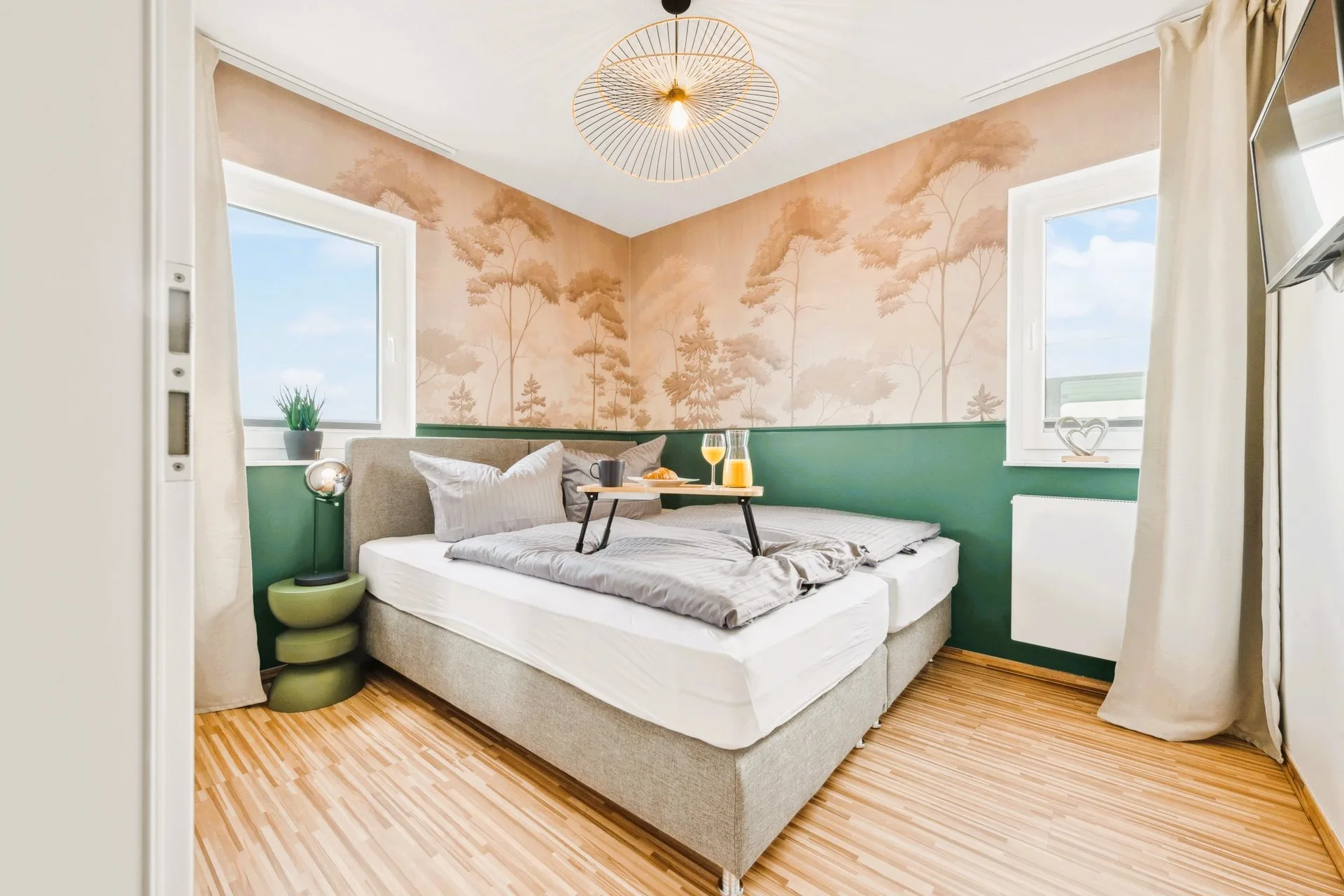 Schlafzimmer mit Waldmotiv-Wandbild und Frühstückstablett