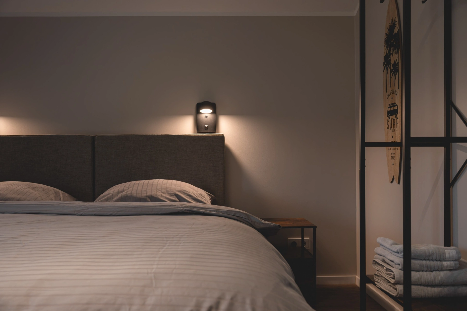 Bett mit Wandleuchte und Handtuchleiter
