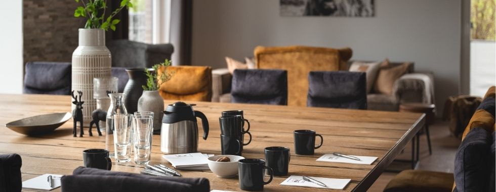 Gedeckter Holztisch mit Kaffeekannen, Tassen und Deko in gemütlicher Wohnatmosphäre