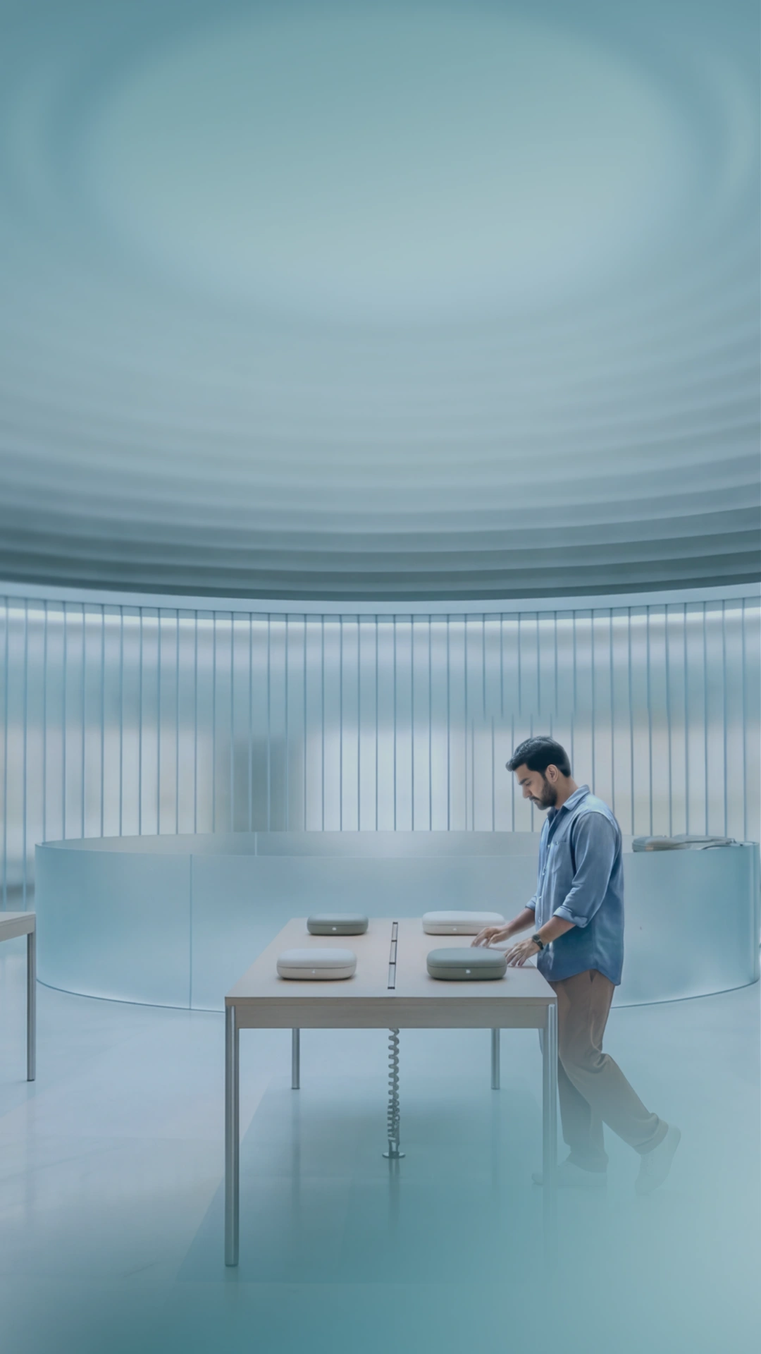 A person interacting with Ventori product cases on a minimalist display table in a modern, circular showroom.