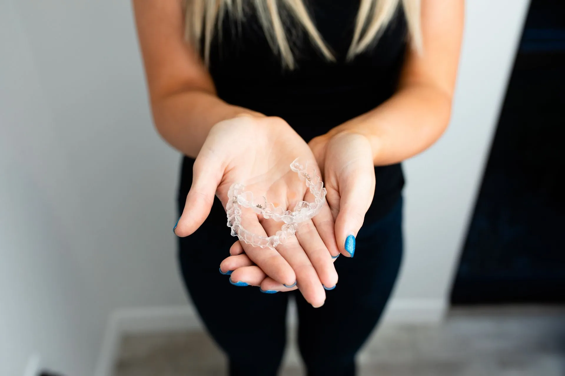 Woman holding a clear dental aligner in her hands.