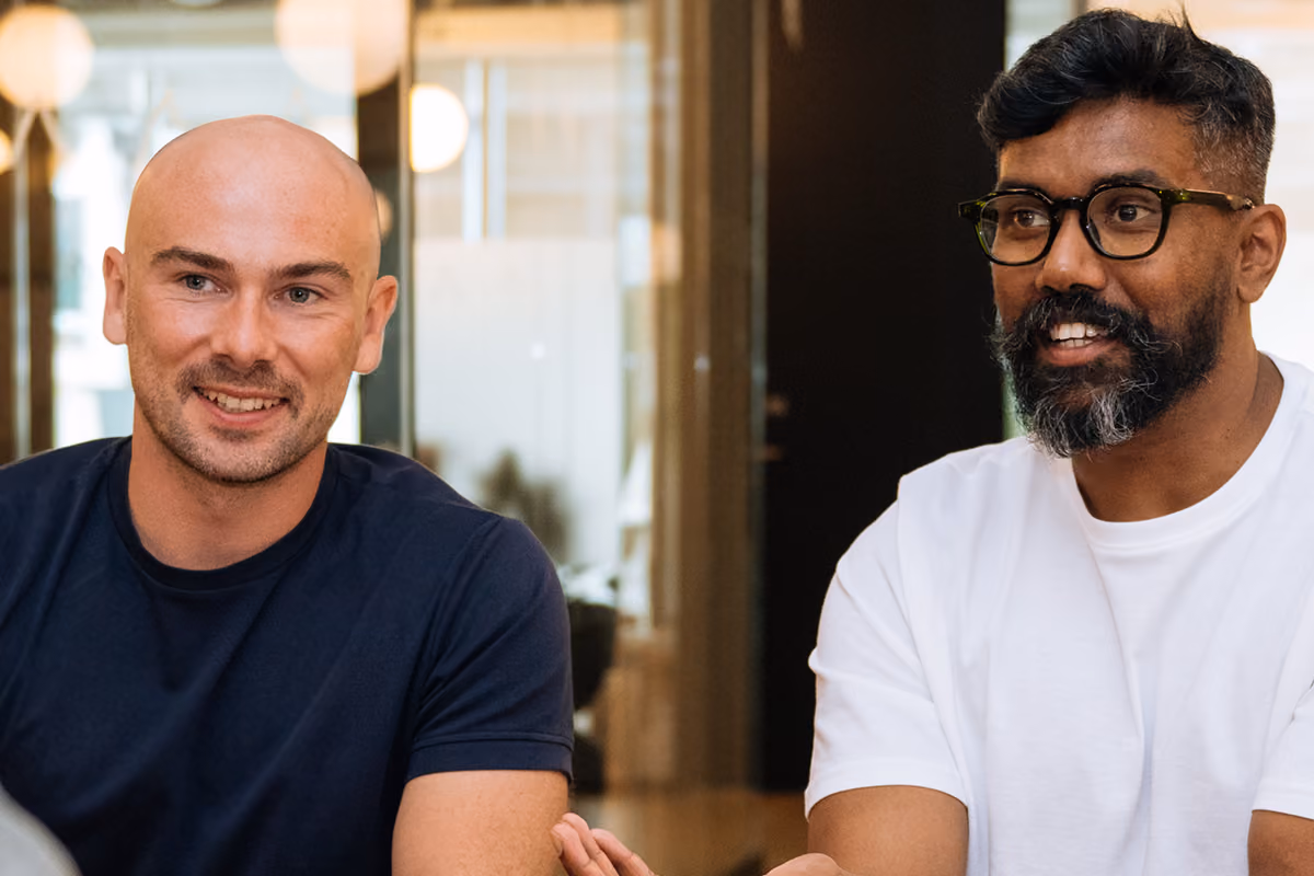 Two colleagues sitting together and smiling during a conversation in a modern office lounge