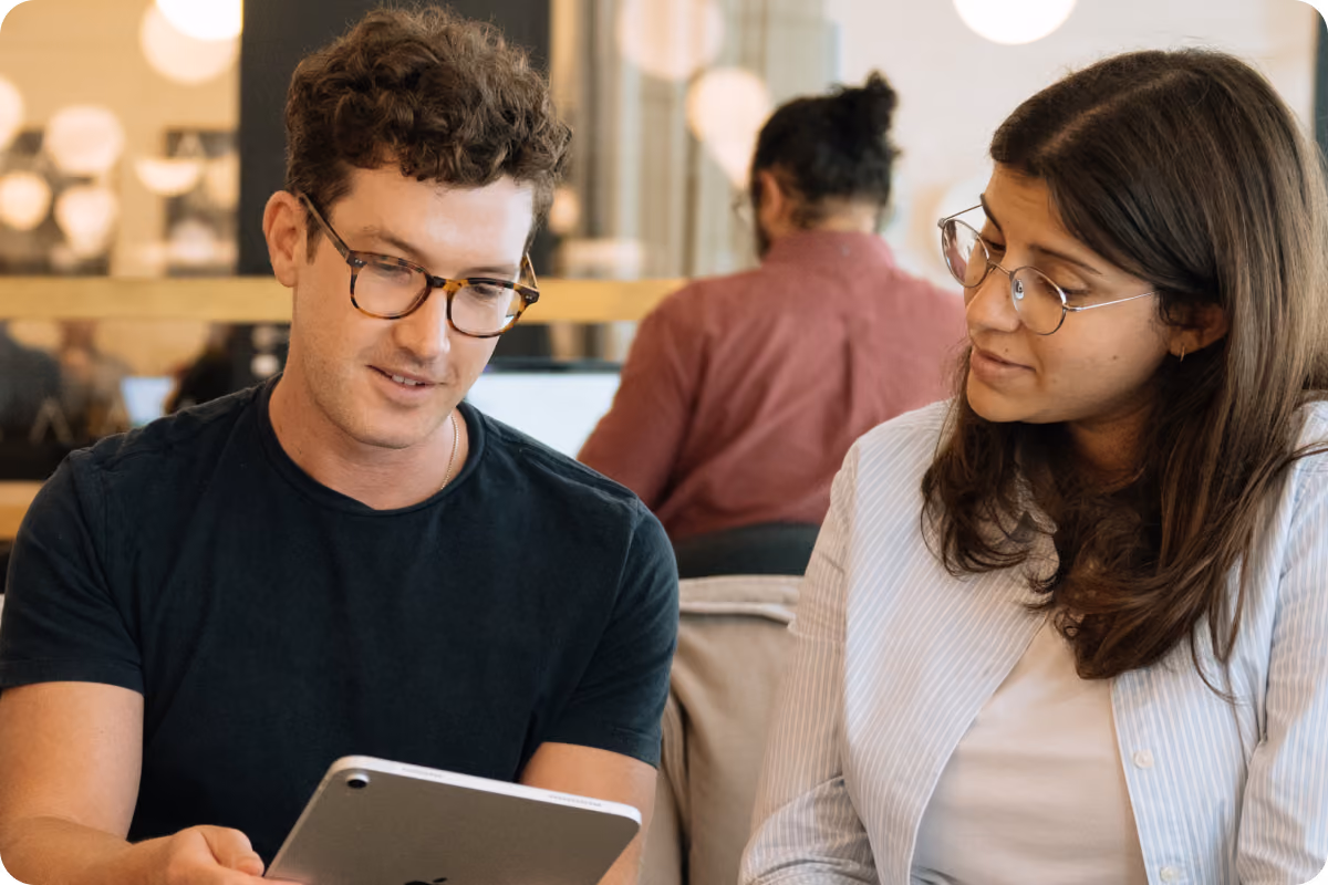 A man and woman looking together at a tablet screen while discussing something in an office setting