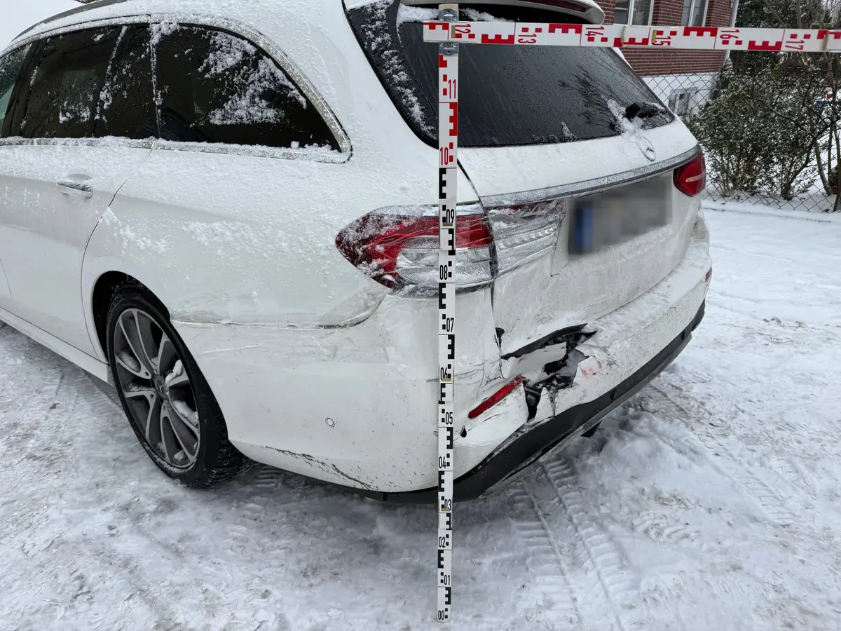 Schadenvermessung am Mercedes E-Klasse T-Modell: Messlatte neben dem aufgerissenen Stoßfänger und dem beschädigten Rücklicht am Heck