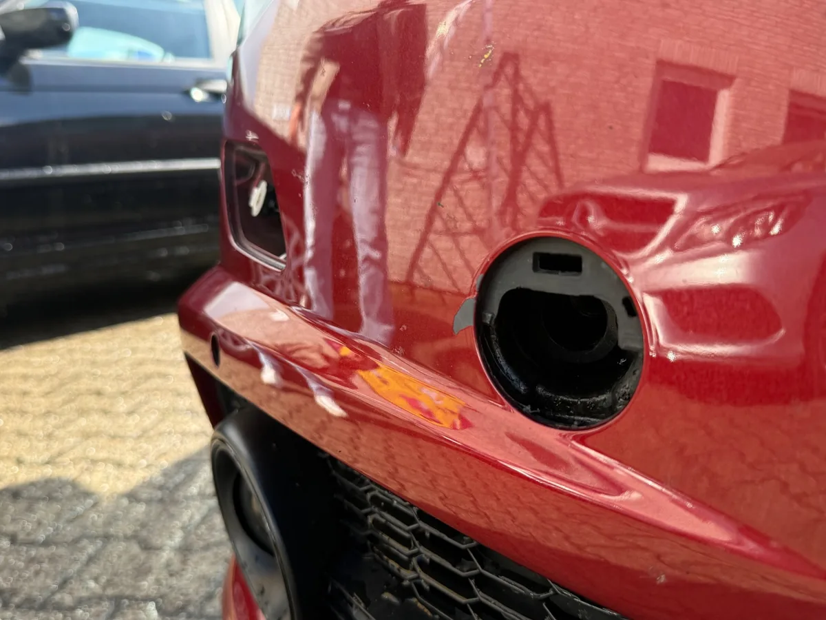 Nahaufnahme des Frontstoßfängers am Audi A6 Avant: Öffnung ohne Abdeckkappe, Lackabplatzer am Rand und beschädigte Aufnahme nach einem Unfall in Kiel