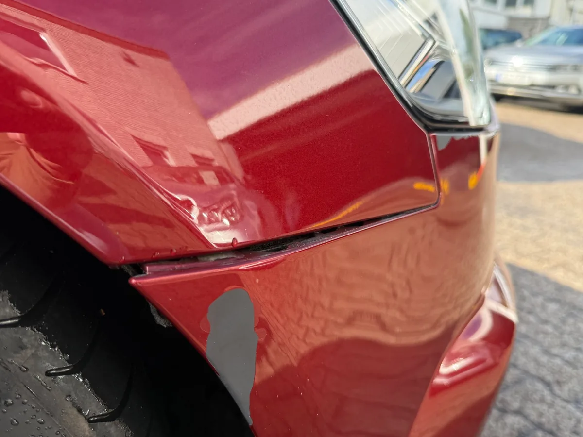 Frontstoßfänger-Ecke am Audi A6 Avant neben dem Scheinwerfer: abgeplatzter Lack bis auf die Grundierung, unebene Oberfläche und offener Spalt am Übergang zum Kotflügel nach einem Unfall in Kiel