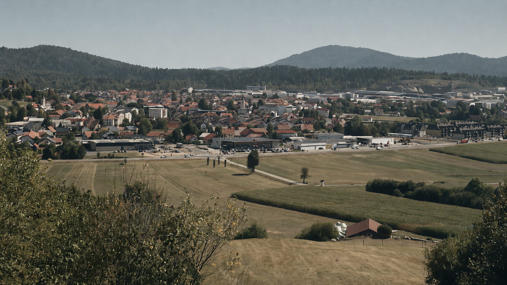 Logatec Sekirica. Pogled na mesto obdan z zelenimi travniki, gozdovi in hribi v ozadju.