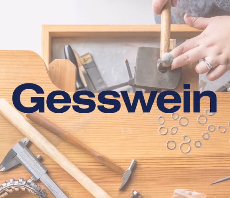Close-up of hands working with metal tools and rings on a wooden surface, focusing on a hammer and metalwork equipment.