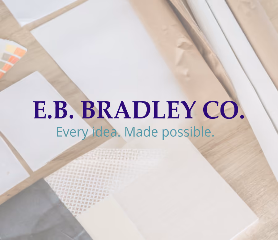 E.B. Bradley Co. logo with the tagline 'Every idea. Made possible.' over a background of various paper and packaging samples on a wooden surface.