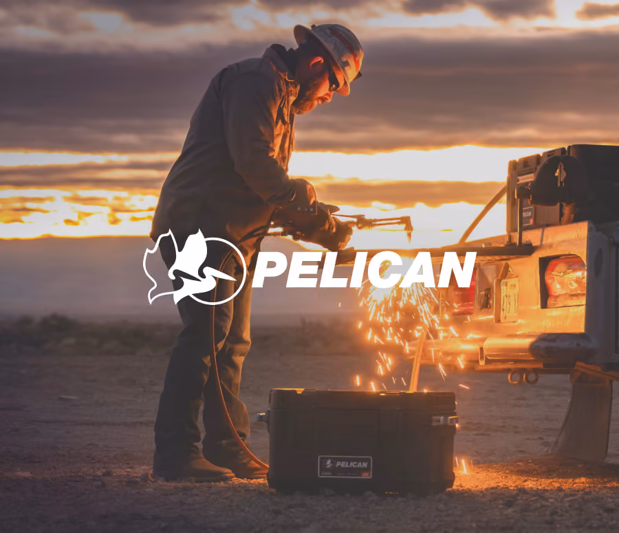 Man wearing protective gear using a welding torch near a vehicle at sunset with sparks flying, a Pelican case on the ground nearby, and the Pelican logo and name overlaid on the image.