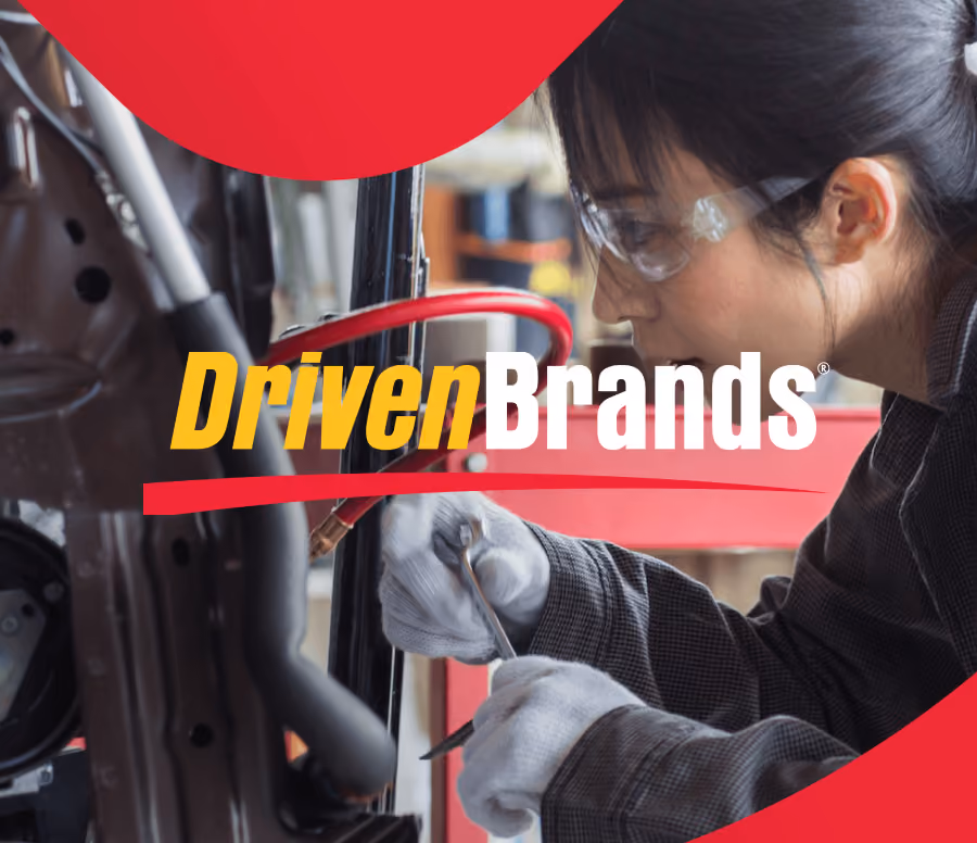 Person with safety glasses and gloves using a wrench to work on machinery with DrivenBrands logo overlayed in yellow and white text and red graphic accents.