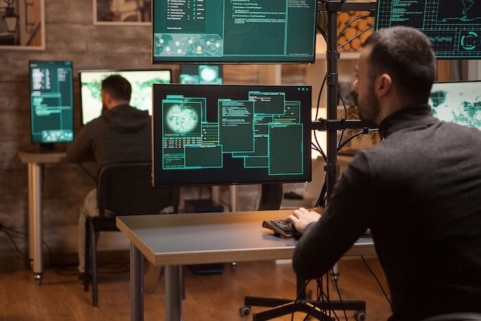 Specialist monitoring cybersecurity alerts across several screens
