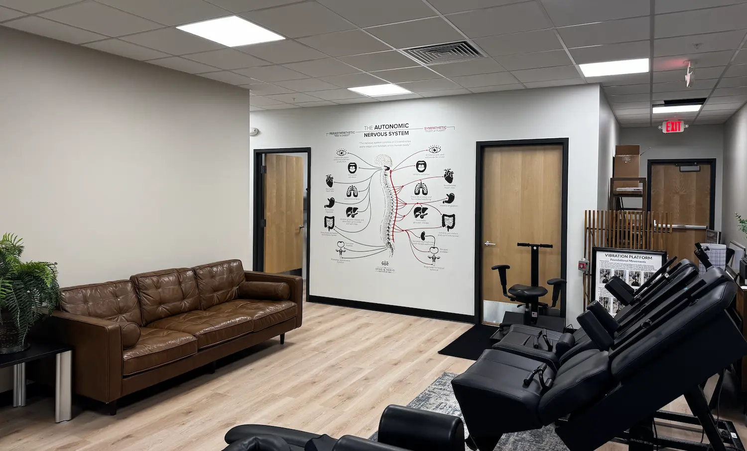 An advanced chiropractic treatment table featuring electronic controls and a screen, situated in a yellow-walled room with a clinical setup.