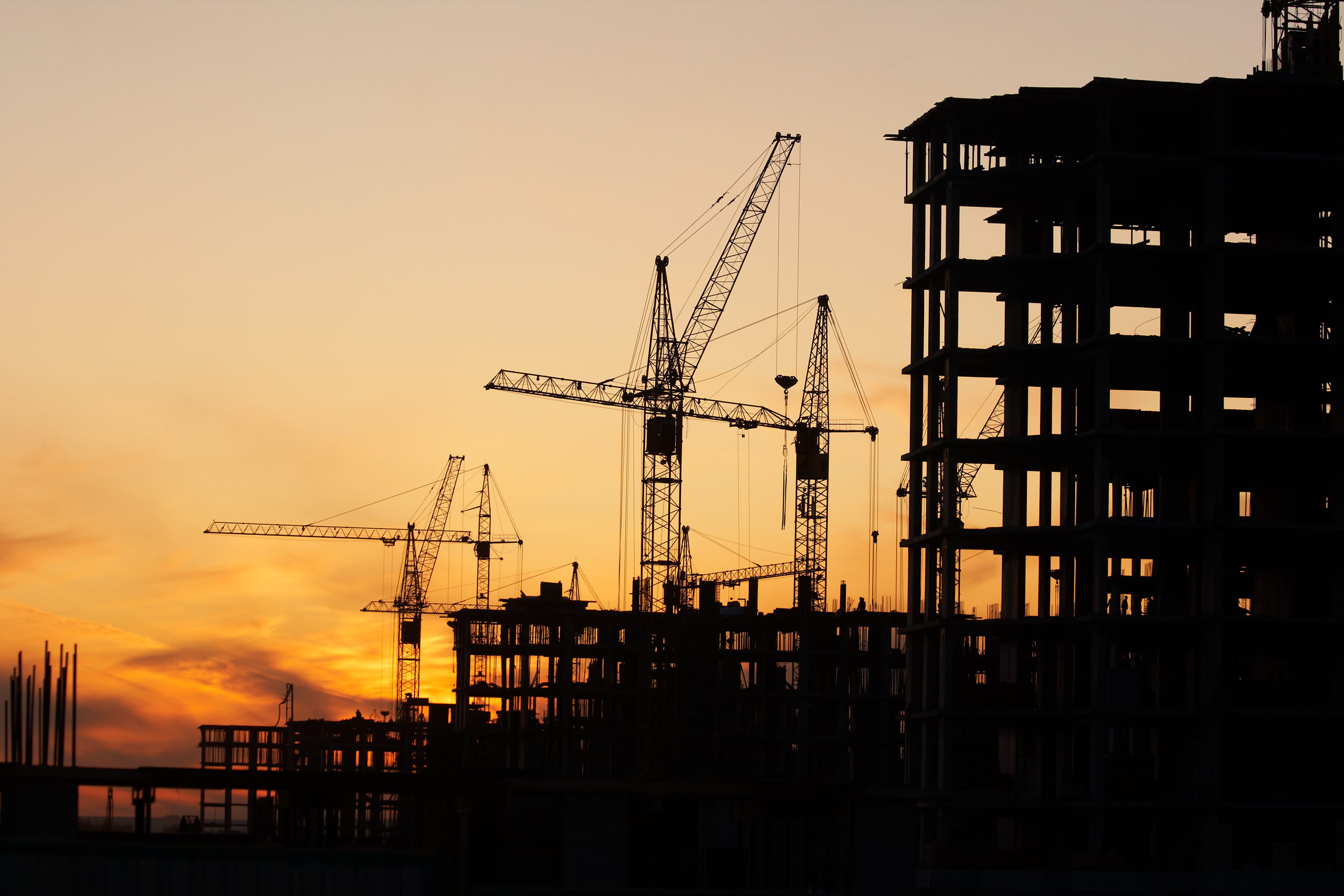 Prédio em construção com guindastes ao pôr do sol