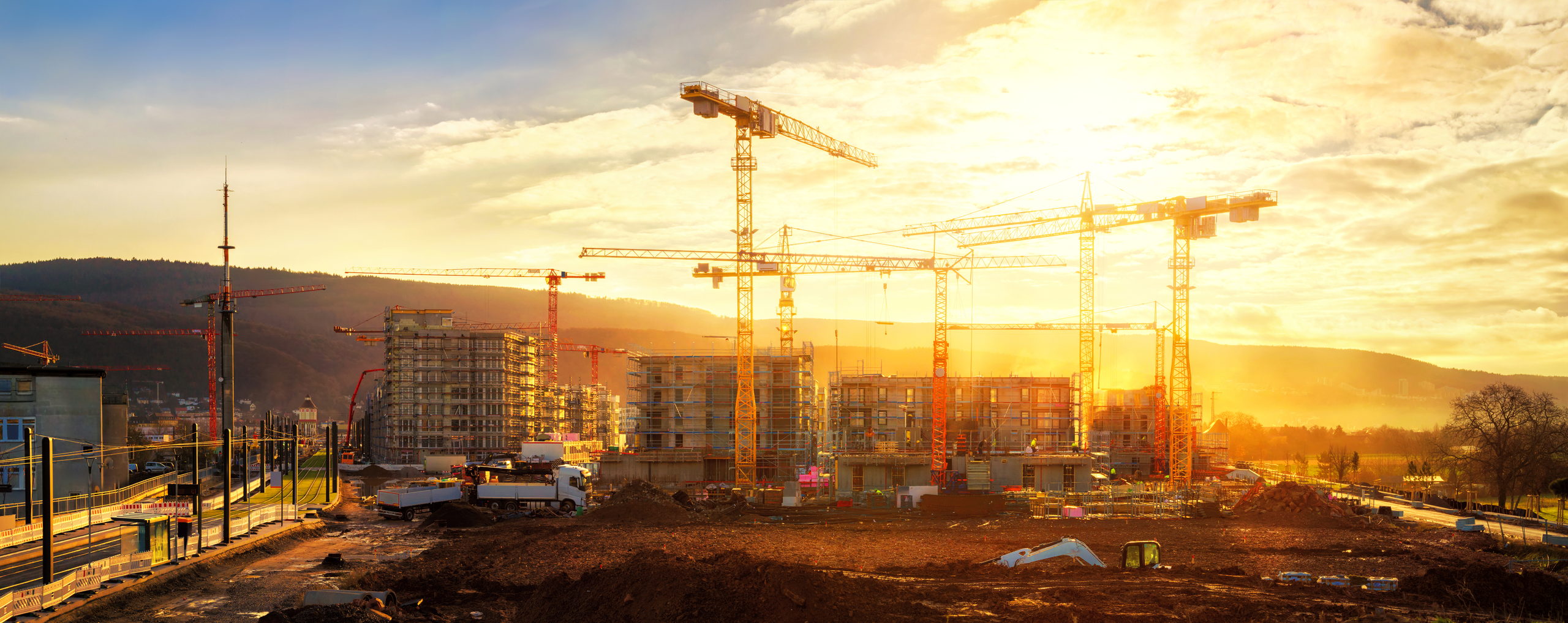 Canteiro de obras com guindastes ao entardecer