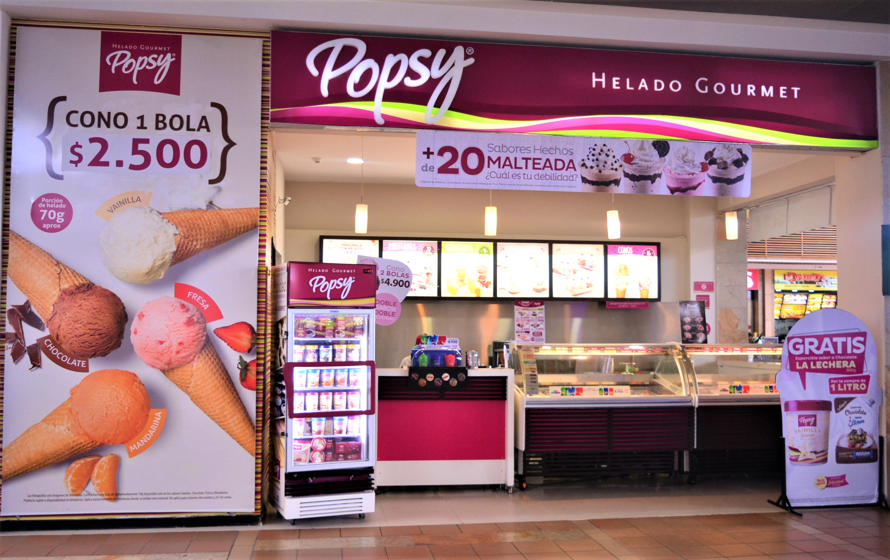 Popsy helado gourmet ice cream shop with menu boards, freezer, and promotional posters for cones and promotions.